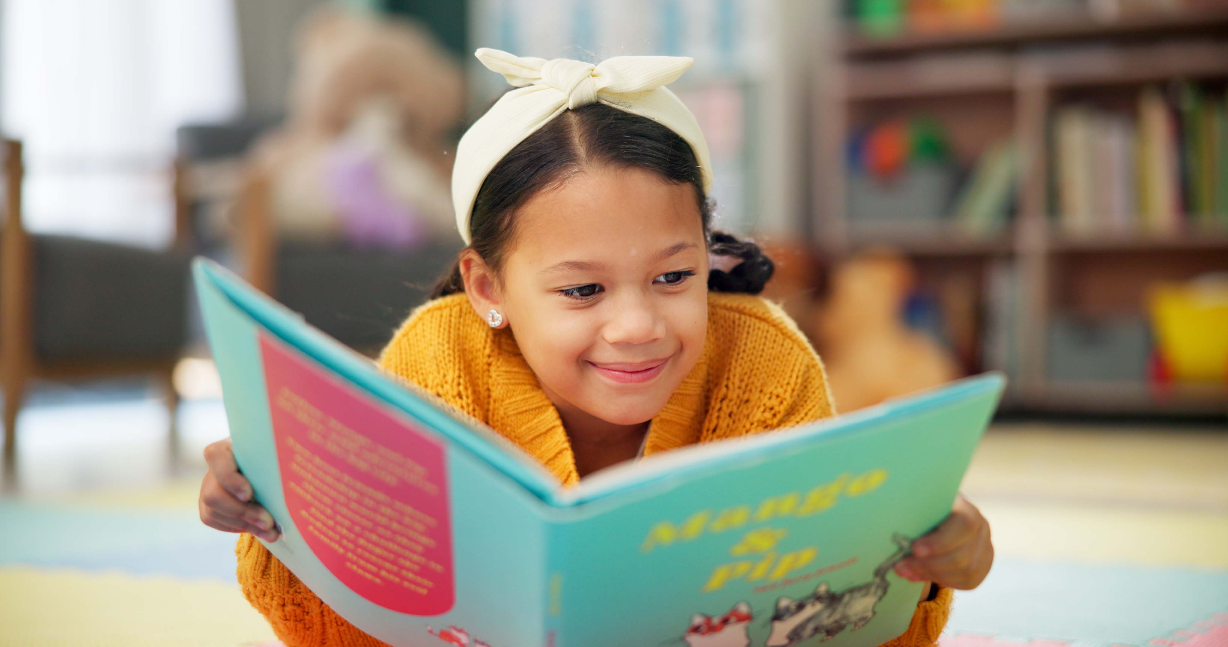 Girl, school and reading book in class, childhood development and growth for vocabulary in kindergarten. Happy, smile and knowledge or information with storybook, learning and fantasy for child stock photo