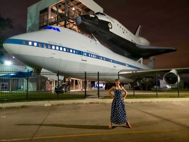 Space science educator in front of NASA space shuttle